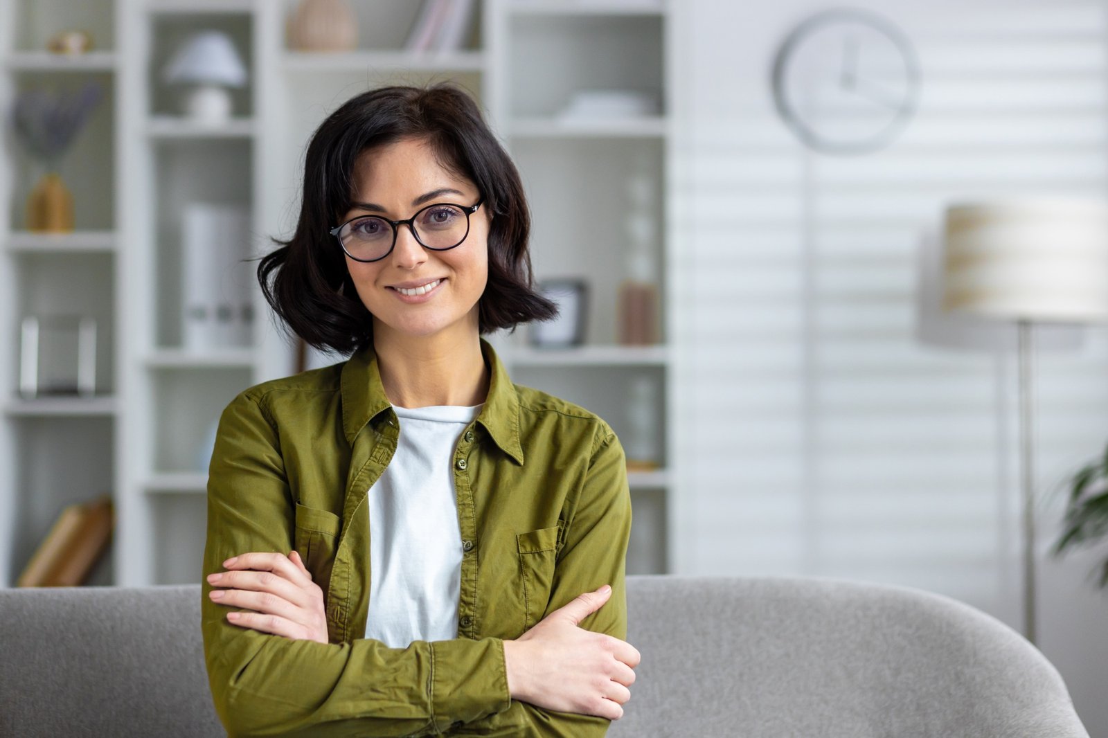 Confident professional woman smiling in a casual office setup, arms crossed